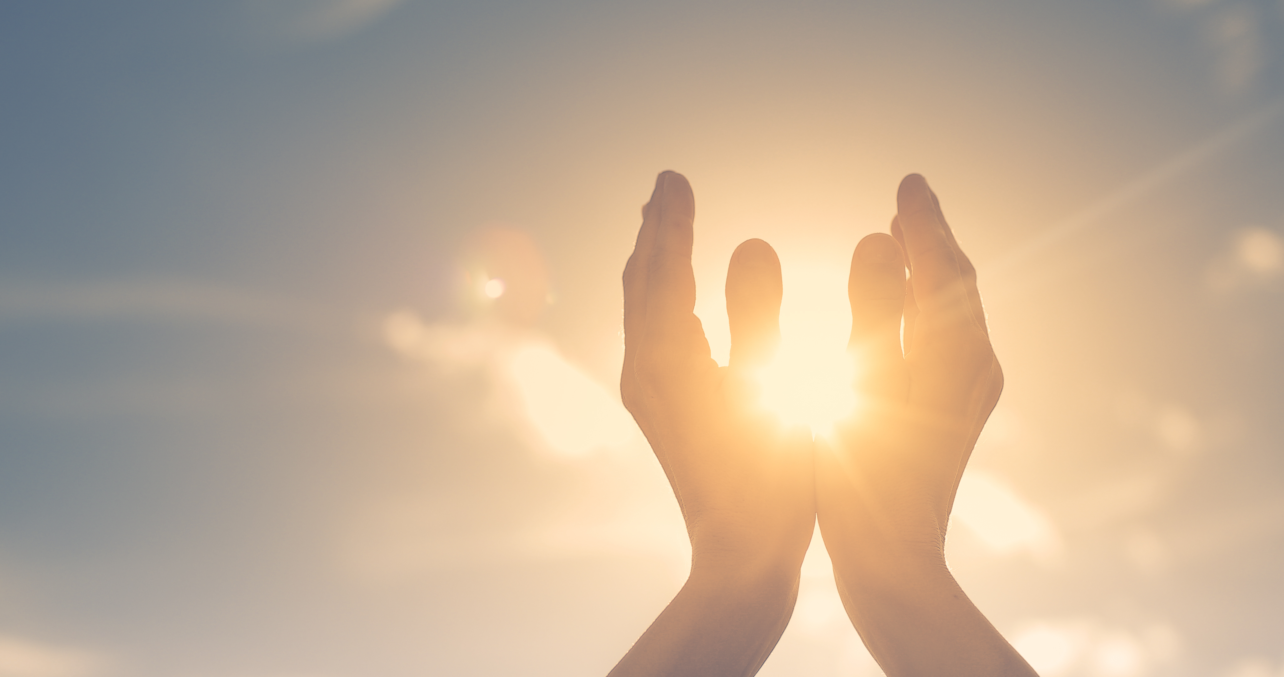 Hands raised toward bright sunlight